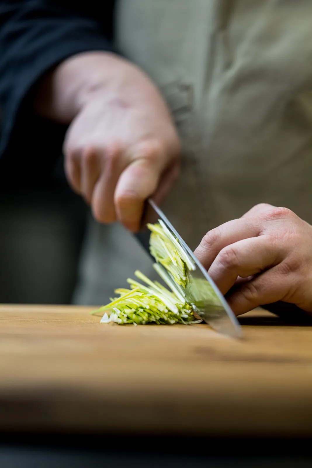 Hands slicing leek — Michelin brigade during catering prep