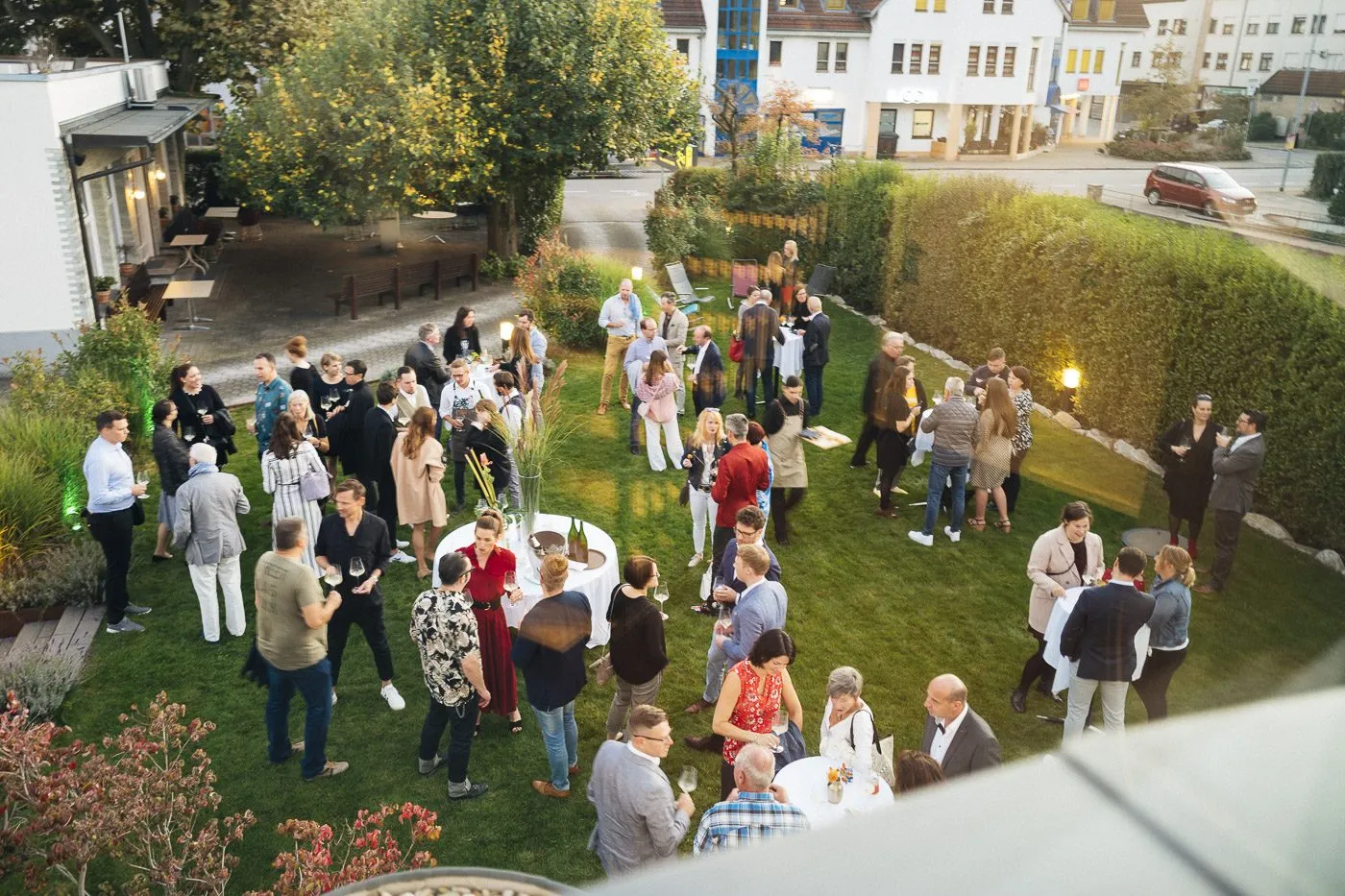 Gartenparty von oben, Gäste an langen Tischen