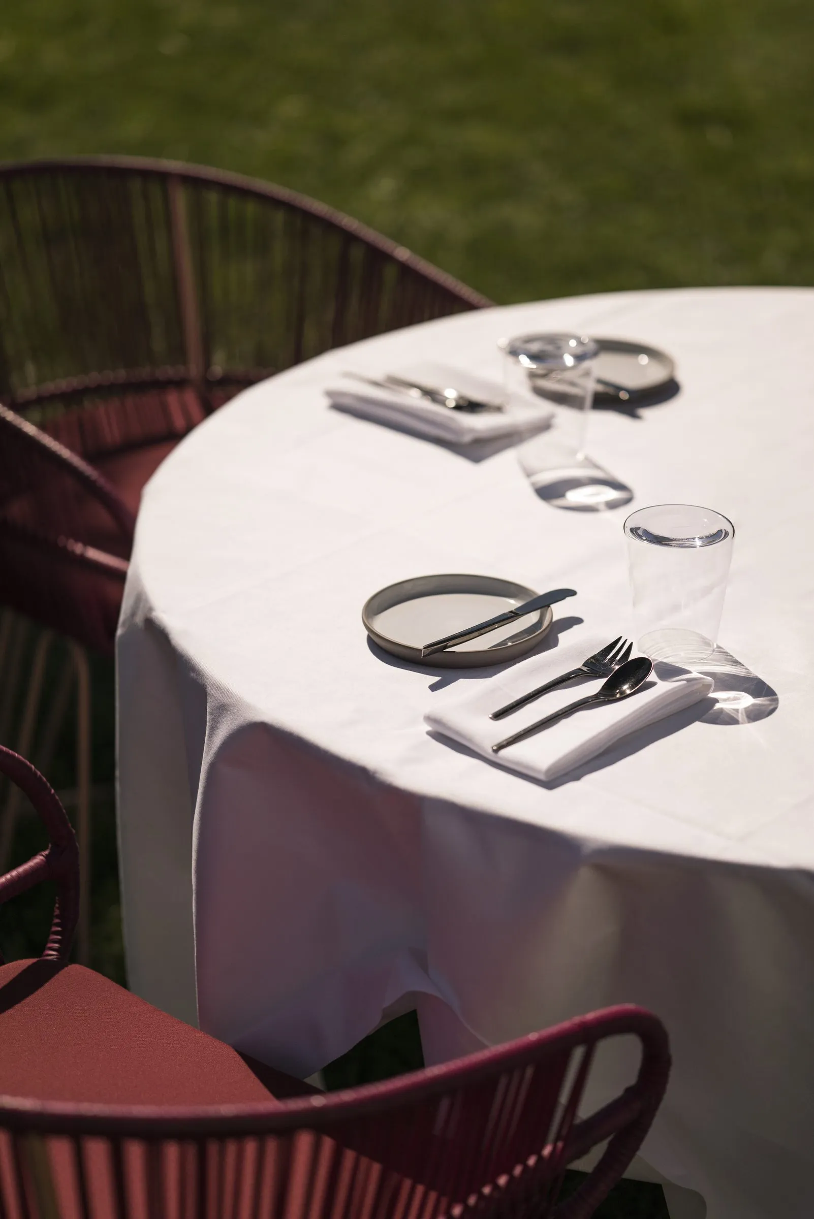 Gedeckter Gartentisch mit roten Stühlen